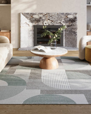 Moderne stue med grafisk designteppe i duse grønntoner og rene linjer – en stilren og balansert interiørløsning.